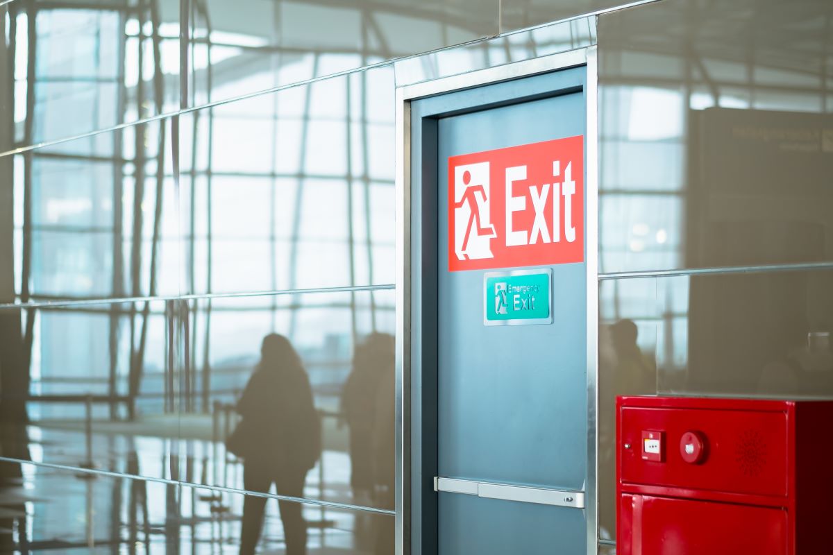 Exit-kyltti ja palosammutin käytävällä – paloturvallisuuskoulutus auttaa toimimaan tulipalossa.